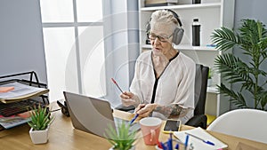 Jovial senior grey-haired business woman tapping into the rhythm at work, gleefully drumming her desk, enjoying music in office
