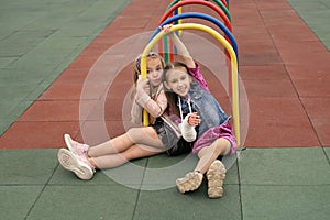 Joy little preschool girl with broken arm and cast on her forearm having fun at children`s sports playground with her friend desp photo