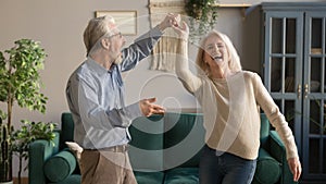 Joyful active old retired romantic couple dancing in living room