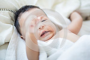 Joyful adorable infant baby boy lying on white blanket