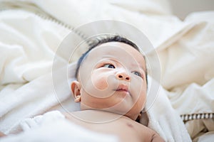 Joyful adorable infant baby boy lying on white blanket