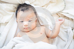 Joyful adorable infant baby boy lying on white blanket