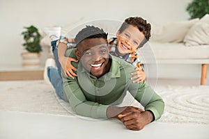 Joyful African American Daddy And Kid Son Posing Lying Indoor