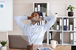 Joyful african american employee resting on his chair