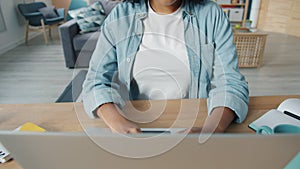 Joyful African American girl enjoying internet content using laptop at home smiling