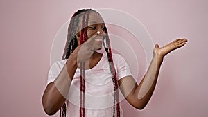 Joyful african american woman confidently presenting, pointing to the side with a beatific smile over an isolated pink background