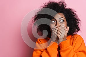 Joyful african american woman covering her mouth and looking aside