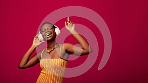 Joyful african american woman listening to music, using wireless headphones