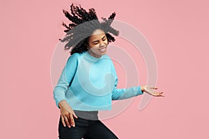 Joyful african american young woman with bright smile dance with invisible guitar over pink background.