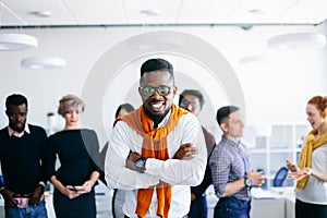 Joyful African CEO standing and crossing his arms with colleagues