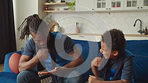 Joyful African family of American football fans watching game live on tv at home