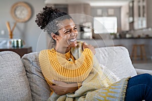 Joyful african woman with blanket on couch laughing