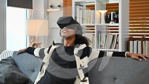 Joyful African woman experiencing opportunities of gaming in virtual reality headset. Futuristic technology concept