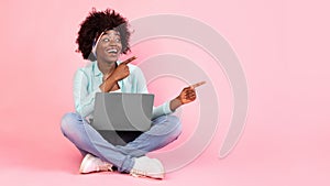 Joyful African Woman With Laptop Pointing Fingers Aside, Pink Background