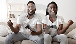 Joyful afro couple celebrating victory in video game