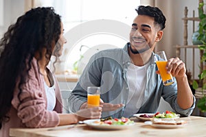 Joyful Arab Couple Enjoying Their Tasty Breakfast And Drinking Juice In Kitchen