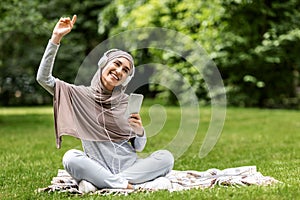 Joyful arab girl listening to music at park