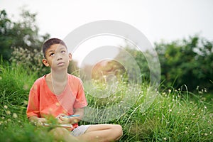 Joyful asian boy student sitting writing and reading book outside on school or park.