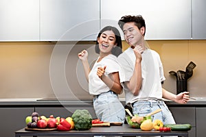 Joyful Asian Couple Dancing Preparing Dinner Having Fun In Kitchen