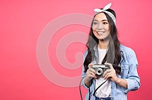 Joyful asian girl taking pictures on a retro vintage camera