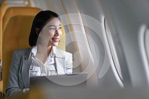 Joyful asian woman sits in the airplane and using laptop while go to travel