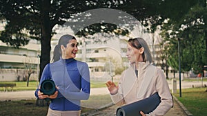 Joyful athletes speaking happily walking park. Cheerful yogini talking outdoors
