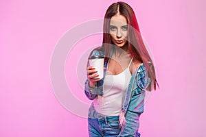 Joyful attractive young woman with positive smile in fashionable youth jeans clothes with cup of tea poses and cute smiles near
