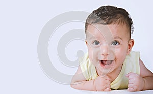 A joyful baby boy lying on his stomach with his head up on a white studio background