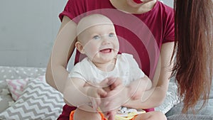 Joyful baby playing in palms with mother at home