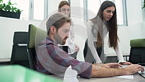 Joyful bearded guy and two young girls are discussing the work plan in the office in the workplace. The senior manager