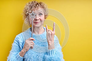 joyful beautiful crazy senior woman with magic wand, showing rock gesture