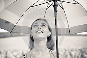 Joyful beautiful girl holding umbrella in sunflower field background