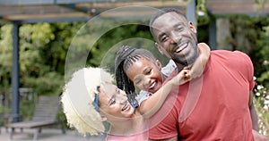 Joyful biracial family shares a close moment in a sunny park.