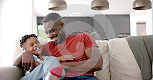 Joyful biracial family shares laughter in a bright living room.