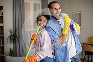 Joyful Black Couple Having Fun Cleaning House And Singing Indoor