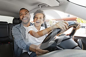 Joyful black father and son spend time together, driving car