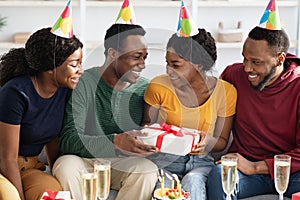Joyful black friends greeting birthday guy at home