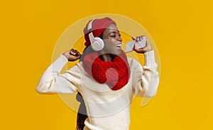 Joyful black girl in headphones listening to music and singing