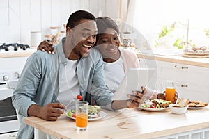 Joyful Black Millennial Couple Using Digital Tablet For Video Call In Kitchen