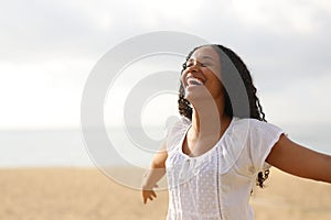 Joyful black woman outstretching arms on the beach