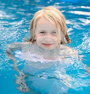 Joyful blond child in swimming pool in summer
