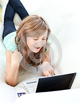 Joyful blond woman using her laptop on the sofa