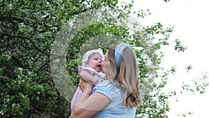 Joyful blonde mother tosses funny baby girl and kisses kid