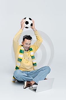 joyful bookmaker with soccer ball sitting