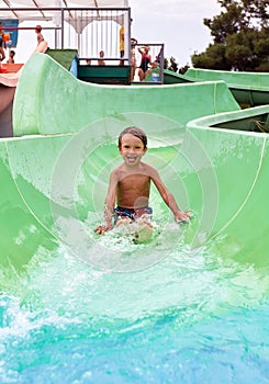 Joyful boy descends from the water slide in the water park, children& x27;s attractions in the water park, water