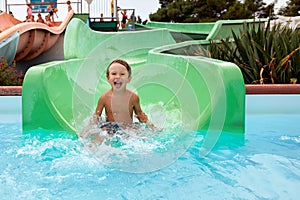 Joyful boy descends from the water slide in the water park, children& x27;s attractions in the water park, water
