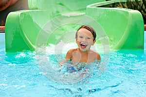 Joyful boy descends from the water slide in the water park, children& x27;s attractions in the water park, water