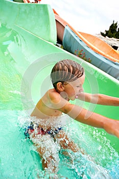 Joyful boy descends from the water slide in the water park, children& x27;s attractions in the water park, water