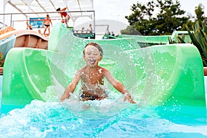 Joyful boy descends from the water slide in the water park, children& x27;s attractions in the water park, water