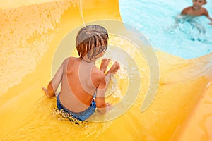 Joyful boy descends from the water slide in the water park, children& x27;s attractions in the water park, water